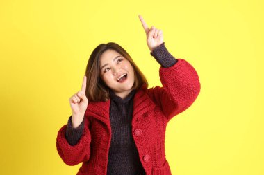 Sarı arka planda sıradan kıyafetlerle duran tombul Asyalı kadın..