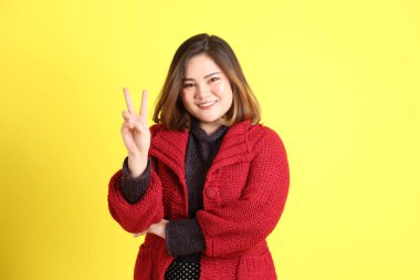 Sarı arka planda sıradan kıyafetlerle duran tombul Asyalı kadın..