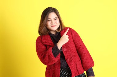 Sarı arka planda sıradan kıyafetlerle duran tombul Asyalı kadın..