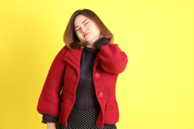 Sarı arka planda sıradan kıyafetlerle duran tombul Asyalı kadın..