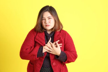 Sarı arka planda sıradan kıyafetlerle duran tombul Asyalı kadın..