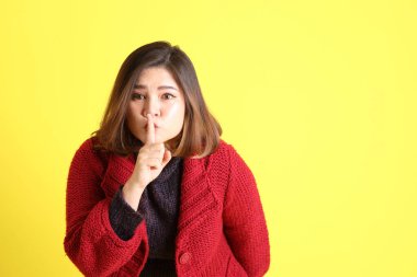 Sarı arka planda sıradan kıyafetlerle duran tombul Asyalı kadın..