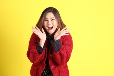 Sarı arka planda sıradan kıyafetlerle duran tombul Asyalı kadın..