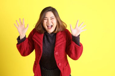 Sarı arka planda sıradan kıyafetlerle duran tombul Asyalı kadın..