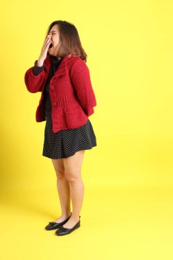 Sarı arka planda sıradan kıyafetlerle duran tombul Asyalı kadın..