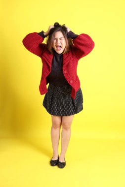 Sarı arka planda sıradan kıyafetlerle duran tombul Asyalı kadın..