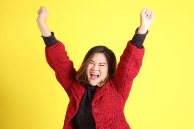 Sarı arka planda sıradan kıyafetlerle duran tombul Asyalı kadın..