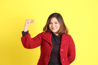 Sarı arka planda sıradan kıyafetlerle duran tombul Asyalı kadın..