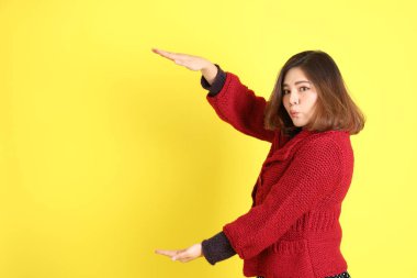 Sarı arka planda sıradan kıyafetlerle duran tombul Asyalı kadın..