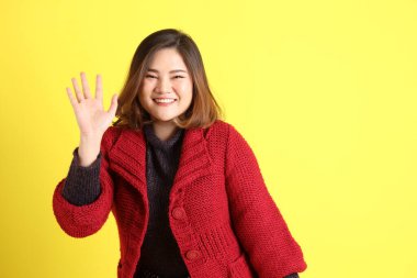 Sarı arka planda sıradan kıyafetlerle duran tombul Asyalı kadın..