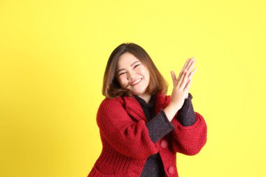 Sarı arka planda sıradan kıyafetlerle duran tombul Asyalı kadın..