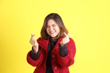 Sarı arka planda sıradan kıyafetlerle duran tombul Asyalı kadın..