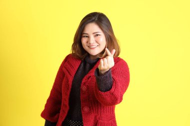 Sarı arka planda sıradan kıyafetlerle duran tombul Asyalı kadın..