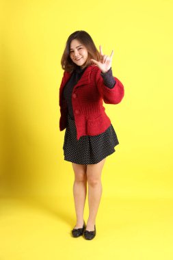 Sarı arka planda sıradan kıyafetlerle duran tombul Asyalı kadın..