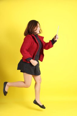 Sarı arka planda sıradan kıyafetlerle duran tombul Asyalı kadın..