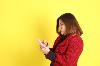 Sarı arka planda sıradan kıyafetlerle duran tombul Asyalı kadın..