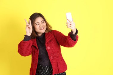 Sarı arka planda sıradan kıyafetlerle duran tombul Asyalı kadın..