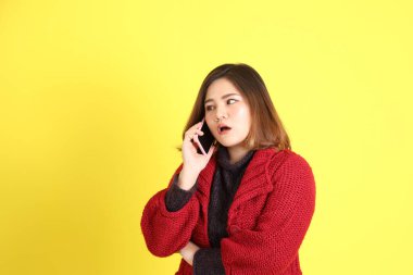 Sarı arka planda sıradan kıyafetlerle duran tombul Asyalı kadın..