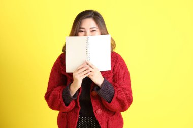 Sarı arka planda sıradan kıyafetlerle duran tombul Asyalı kadın..