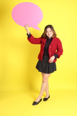 Sarı arka planda sıradan kıyafetlerle duran tombul Asyalı kadın..