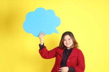 Sarı arka planda sıradan kıyafetlerle duran tombul Asyalı kadın..