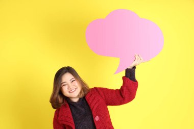 Sarı arka planda sıradan kıyafetlerle duran tombul Asyalı kadın..