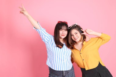 Pembe arka planda duran Asyalı mutlu kardeş..