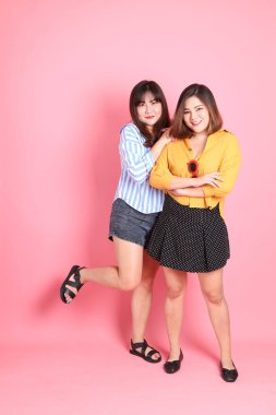 The Asian happy sibling standing on the pink background.