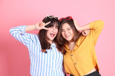 Pembe arka planda duran Asyalı mutlu kardeş..