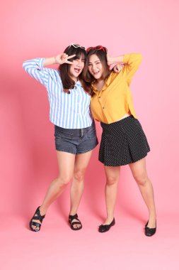 Pembe arka planda duran Asyalı mutlu kardeş..