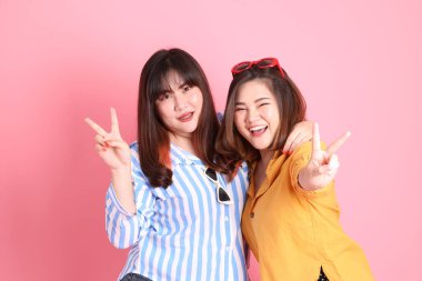 Pembe arka planda duran Asyalı mutlu kardeş..