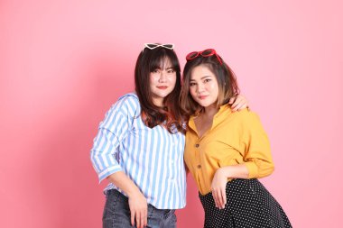 Pembe arka planda duran Asyalı mutlu kardeş..