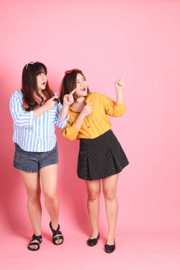 Pembe arka planda duran Asyalı mutlu kardeş..