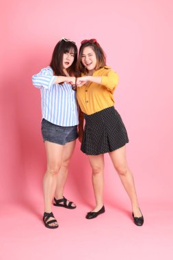 Pembe arka planda duran Asyalı mutlu kardeş..