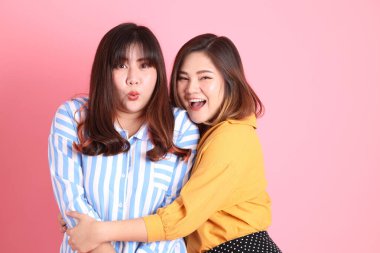 Pembe arka planda duran Asyalı mutlu kardeş..