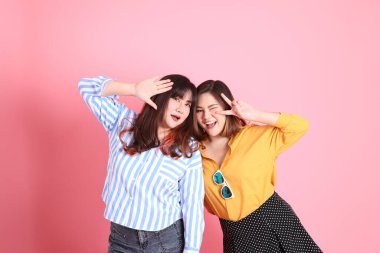 Pembe arka planda duran Asyalı mutlu kardeş..