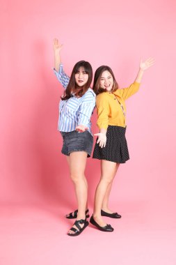 Pembe arka planda duran Asyalı mutlu kardeş..