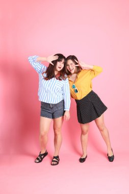 Pembe arka planda duran Asyalı mutlu kardeş..