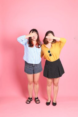 Pembe arka planda duran Asyalı mutlu kardeş..