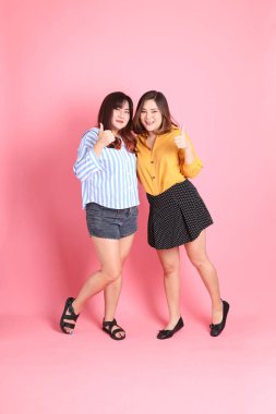 Pembe arka planda duran Asyalı mutlu kardeş..