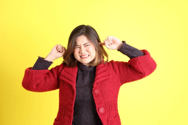 Sarı arka planda sıradan kıyafetlerle duran tombul Asyalı kadın..