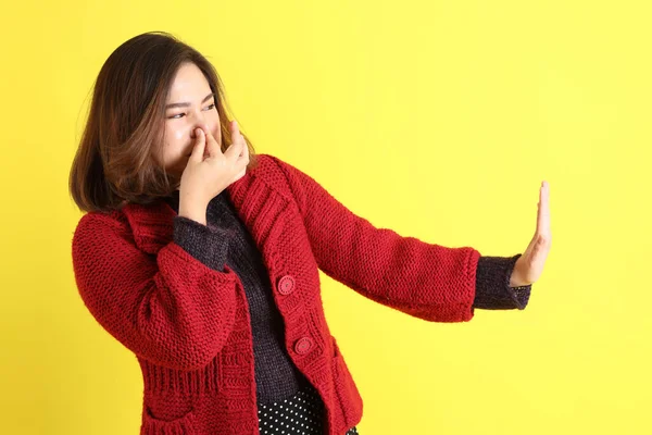 Sarı arka planda sıradan kıyafetlerle duran tombul Asyalı kadın..