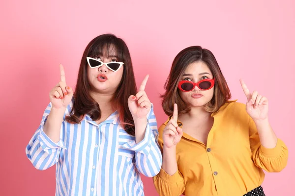 Pembe arka planda duran Asyalı mutlu kardeş..