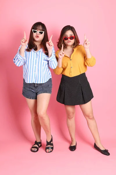 Pembe arka planda duran Asyalı mutlu kardeş..