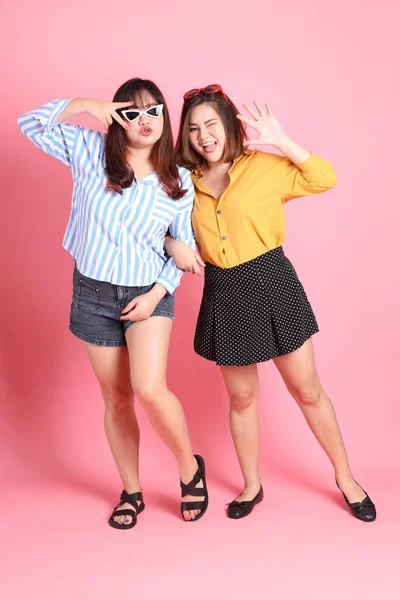 Pembe arka planda duran Asyalı mutlu kardeş..