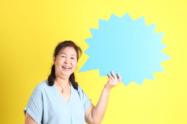 Sarı arka planda açık mavi gömlek giyen Asyalı son sınıf öğrencisi..