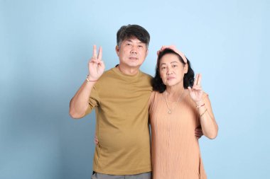 Mavi arka planda sıradan giysileri olan yakışıklı, son sınıf Asyalı çift..