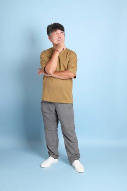 Mavi arka planda sıradan giyinmiş kıdemli Asyalı adam..