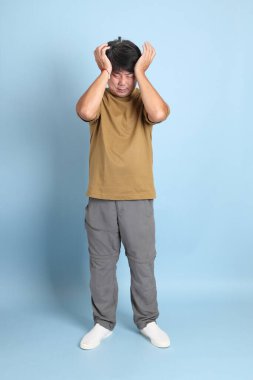 Mavi arka planda sıradan giyinmiş kıdemli Asyalı adam..