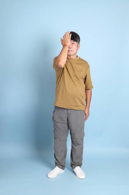 Mavi arka planda sıradan giyinmiş kıdemli Asyalı adam..